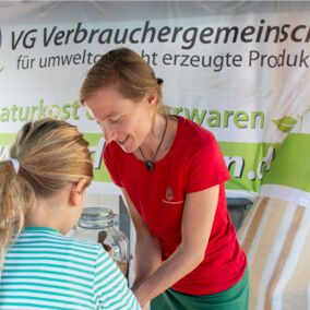 Mitarbeiterin der VG Dresden mahlt mit einem Mädchen Getreide