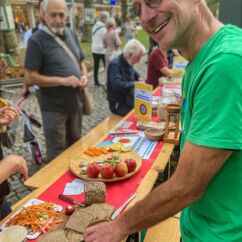 Mitarbeiter der VG Dresden steht an einem Tisch und schneidet Brot, dahinter geschnittenes Obst und Gemüse