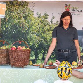 Mitarbeiterin von Senst Biofrucht spricht mit Kind auf dem Regionalfest
