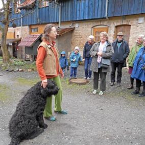 Mann mit Hund spricht vor einer Gruppe Menschen auf Biohof