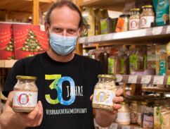Mitarbeiter der Verbrauchergemeinschaft Dresden zeigt zwei Gläser mit Produkten von Unverpackt für Alle