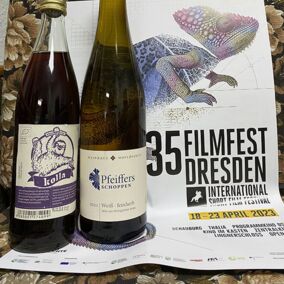 Eine Flasche Bio-Limonade und Bio-Wein stehen vor einem Poster des 35. Filmfest Dresden