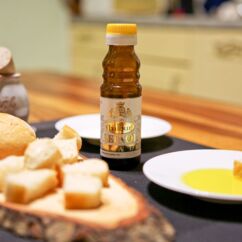 Bio-Leinöl von Balbur steht auf einem Tisch, daneben Brotstücke und Teller