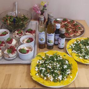 Quarkdessert in Gläsern, grüner Salat, gelbe Bete-Carpaccio und Bruschetta mit Bio-Ölen und Aroma-Öl von Bio Planète auf einem Tisch