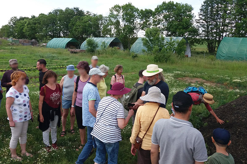 Eine Gruppe Menschen besucht gemeinsam mit Oliver Leipacher die Felder auf dem Auenhof