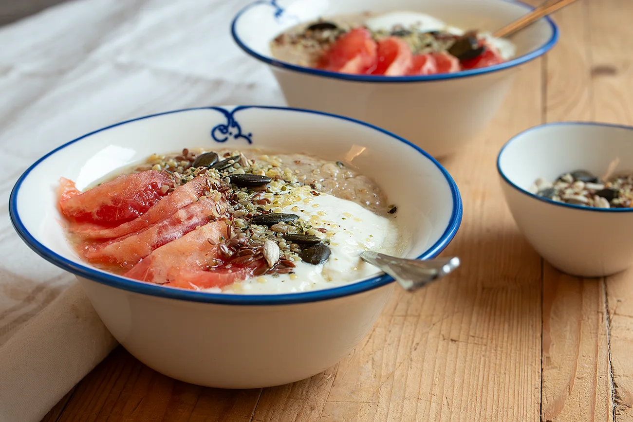 zwei Schüsseln Porridge mit Grapefruit, Joghurt und Saaten