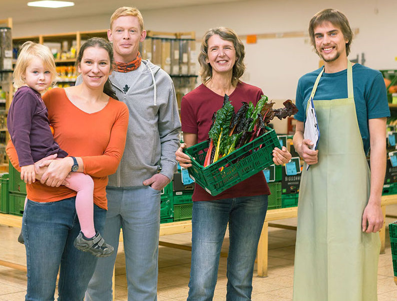Mitarbeiter, Lieferantin und Mitglieder der VG Dresden vor Gemüsekisten im Biomarkt
