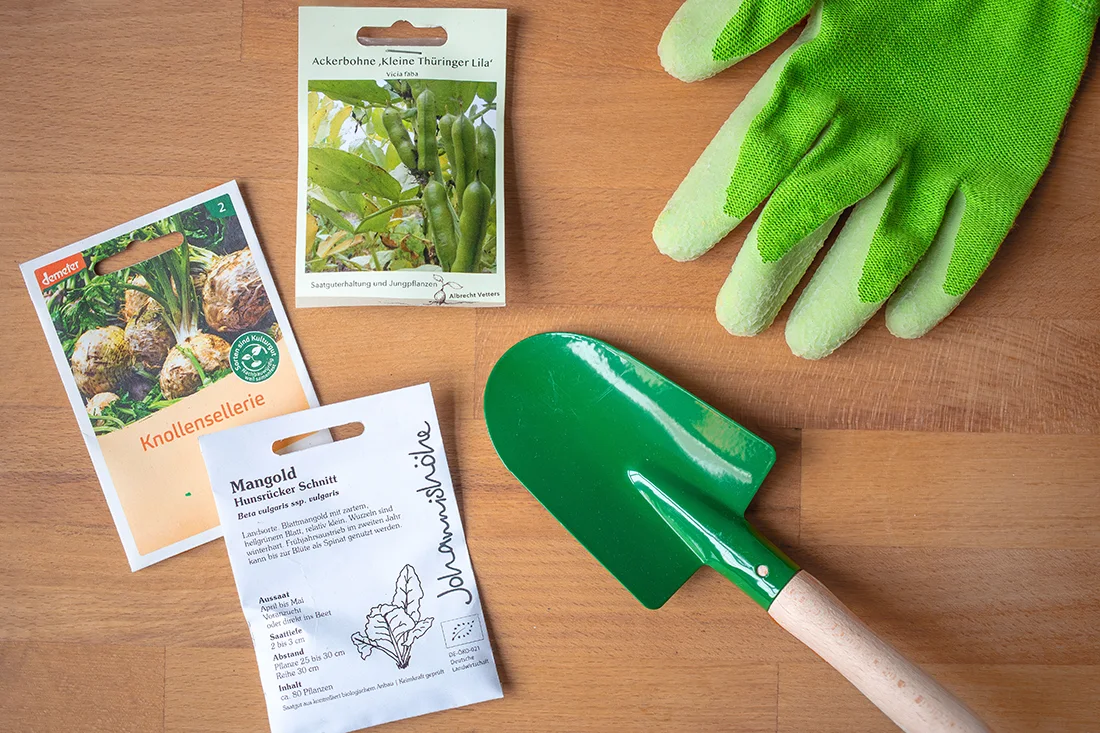 Tütchen mit Bio-Saatgut, Handschuhe und eine Schaufel